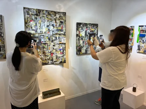 Visitors using a rusted frame or magnifying glass to peer into the texture of the canvas